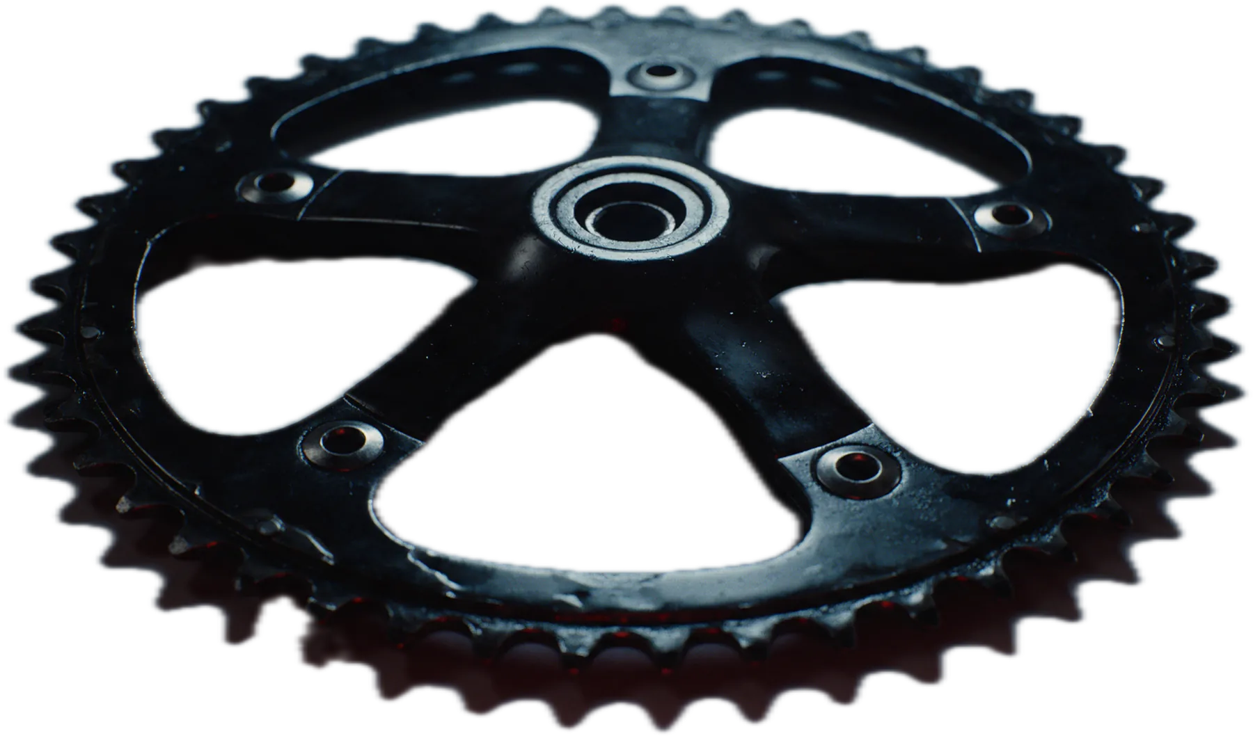 A worn black bicycle chainring, close up.